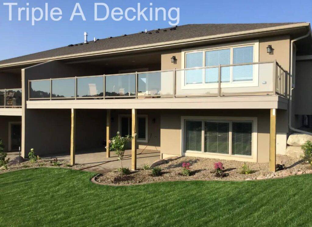 Two-story house featuring a balcony with glass railing and landscaped yard.