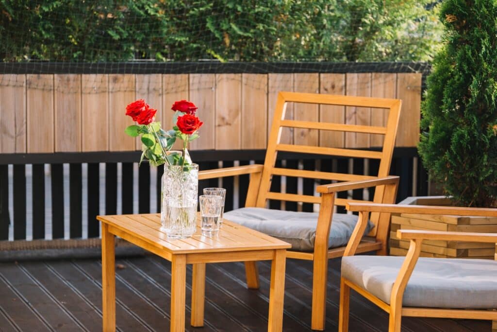 A composite deck with outdoor furniture with roses on the table.