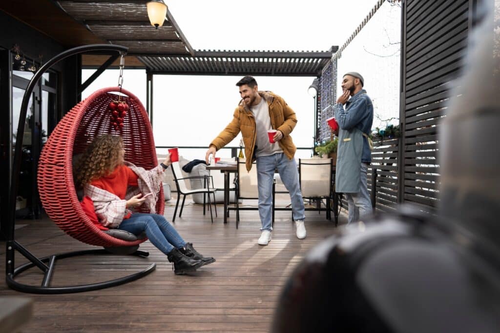 A group of people having fun on a big deck with outdoor furniture and a sunshade.